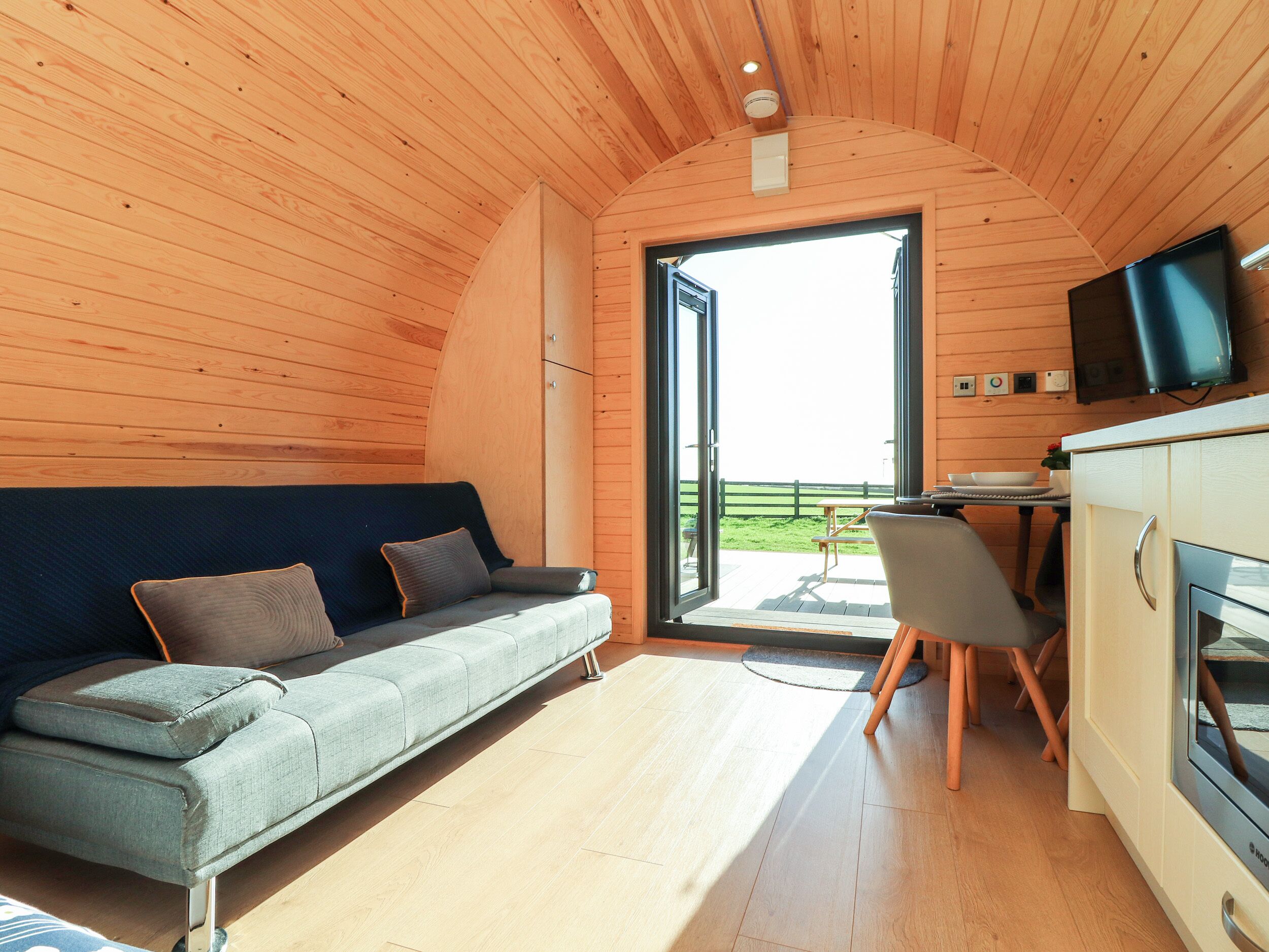 L’intérieur d’un chalet confortable, avec un canapé, une table à manger et un téléviseur.