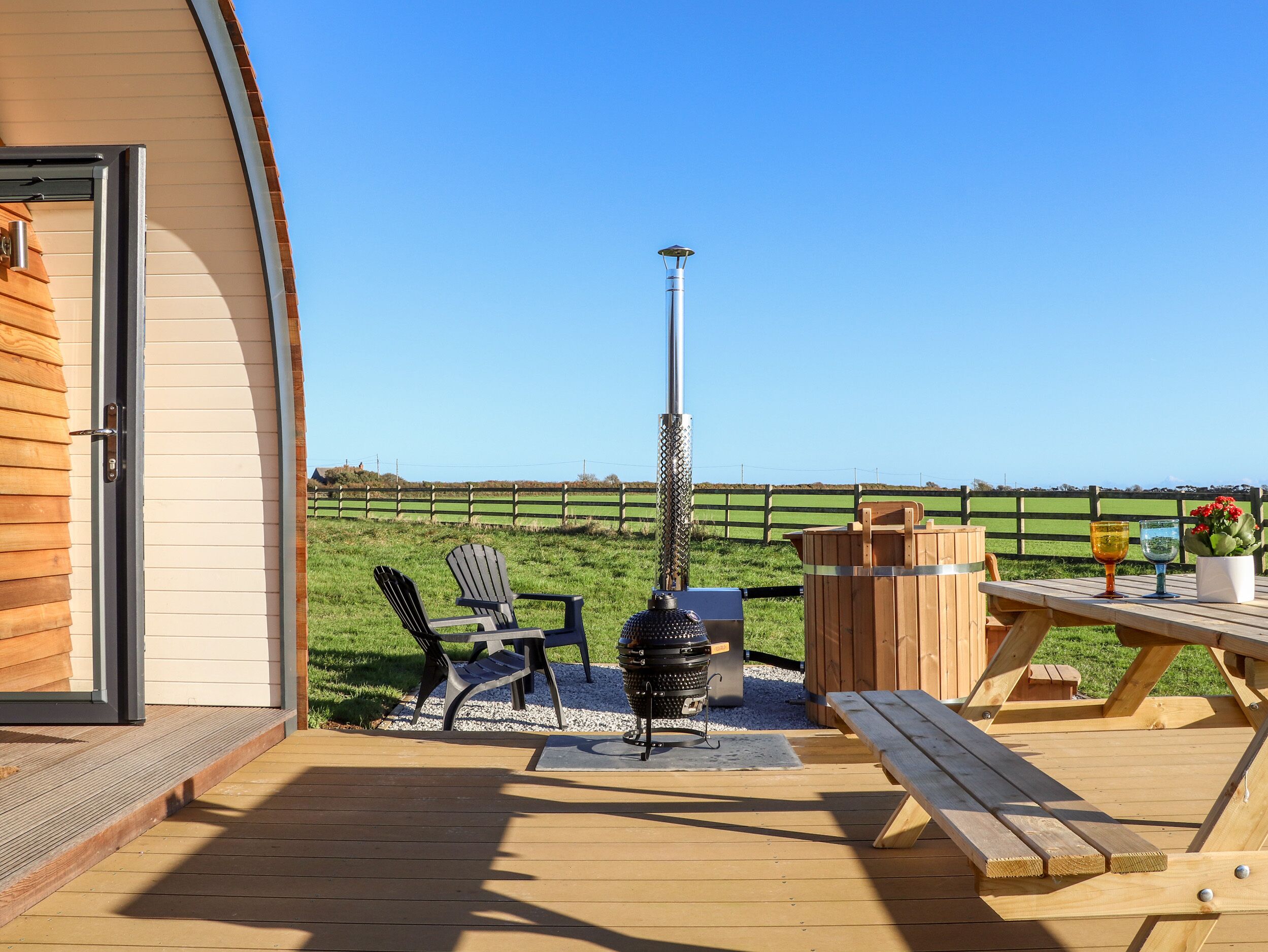 A wooden deck with a grill, chairs, and a table.