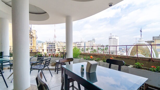 A rooftop terrace with a glass table, chairs, and a view of the cityscape. - Hotel Astoria Real (Cali)