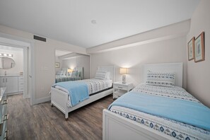 A bedroom with two beds, a vanity with a mirror, and a walk-in closet. - Pelicans Roost 107: Corner Unit with Gulf Views! (Sanibel)