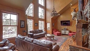 A spacious living room with a large leather sofa, a fireplace with antlers, and a stone wall. - Great Escape - shared pool (Lead)