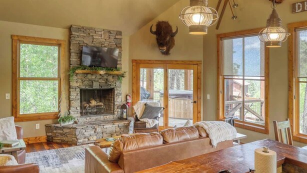A cozy living room with a stone fireplace, leather sofa, and large windows. - Great Escape - shared pool (Lead)