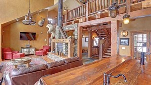 A spacious living area with a large wooden bar, leather seating, and a stone fireplace. - Great Escape - shared pool (Lead)