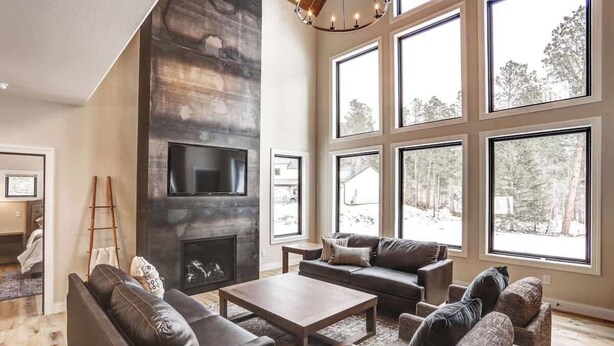 Ein geräumiges Wohnzimmer mit Kamin, großen Fenstern und modernem Design.