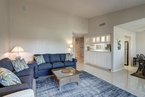 A modern living room with a blue sofa, a coffee table, and a patterned rug. - Dock Holiday 2 Bedroom Condo by Redawning (Rockport)