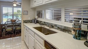 A kitchen with white cabinets, a large sink, and a window with blinds. - Dock Holiday 2 Bedroom Condo by Redawning (Rockport)