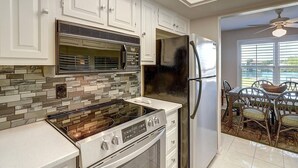 A kitchen with white cabinets, a stainless steel refrigerator, a microwave, and a stove. - Dock Holiday 2 Bedroom Condo by Redawning (Rockport)