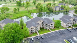 A residential area with apartment buildings, a parking lot, and a golf course in the background. - Fairway Heights 2 Bedroom Condo by RedAwning (Branson)