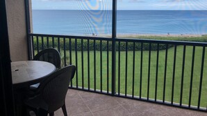 Un balcon avec vue sur l’océan, une table et des chaises.