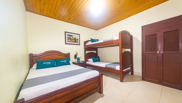 A room with two wooden beds, a wooden wardrobe, and a framed picture on the wall. - Ayenda Pakande (Popayán)