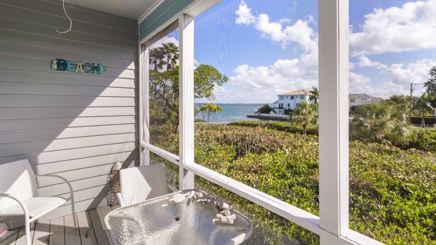 A covered outdoor seating area with a view of the beach and ocean. - Tranquil Bay Views – Cedars East #812 by RVA (Longboat Key)