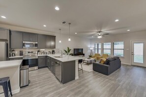 A modern kitchen with a central island, stainless steel appliances, and pendant lighting. - Your Vibrant Dallas Getaway Home (Dallas)