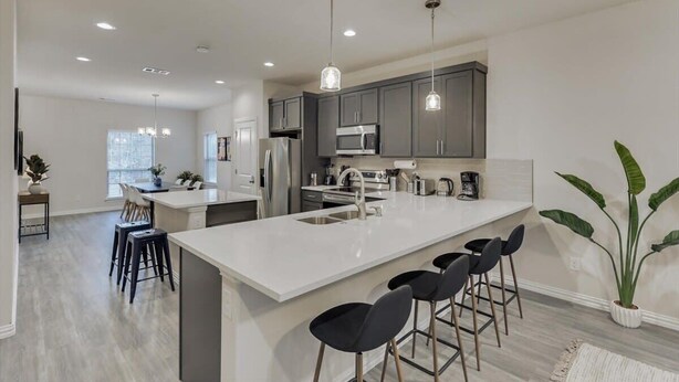 A modern kitchen with a large island, bar stools, and a potted plant. - Your Vibrant Dallas Getaway Home (Dallas)
