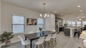 A modern kitchen with a central island, white chairs, and a dining table. - Your Vibrant Dallas Getaway Home (Dallas)