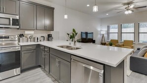 A modern kitchen with stainless steel appliances, a large island, and a dining area with a sofa and chairs. - Your Vibrant Dallas Getaway Home (Dallas)