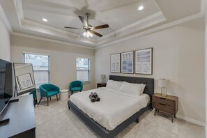 A bedroom with a bed, a desk, a chair, a ceiling fan, and artwork on the wall. - Your Vibrant Dallas Getaway Home (Dallas)