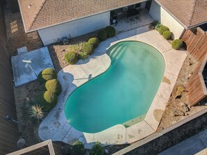 An aerial view of a residential backyard with a swimming pool, surrounded by a wooden deck and various plants. - Spacious and Modern Home with Private Pool (Plano)