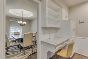A dining area with a chandelier, a table with chairs, and a kitchen with white cabinetry.