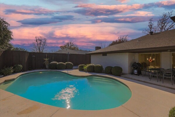 A backyard with a swimming pool, a barbecue area, and a patio with outdoor furniture. - Spacious and Modern Home with Private Pool (Plano)