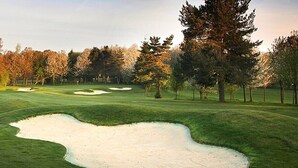 Campo de golf con búnkeres de arena y árboles.