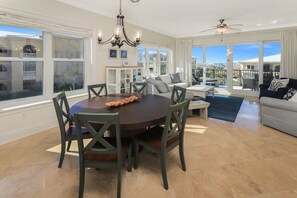 A spacious dining area with a round table, chairs, and a chandelier.