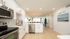 A modern kitchen with white cabinetry, stainless steel appliances, and a central island. - Island Time | Luxury Beach Condo w/ Pool & Hot Tub (Key West)