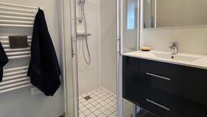A modern bathroom with a glass-enclosed shower, a white tiled floor, a black towel rack, and a mirror above the sink. - Apt With Panoramic View Near Vauban City (Briançon)