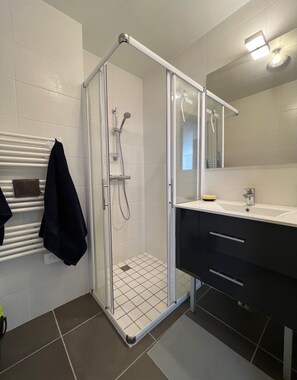A modern bathroom with a glass-enclosed shower, a white tiled floor, a black towel rack, and a mirror above the sink. - Apt With Panoramic View Near Vauban City (Briançon)
