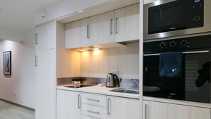Une cuisine moderne avec des meubles blancs, un four encastré et un micro-ondes.