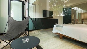 Une chambre à coucher moderne avec un lit, une petite table, une chaise et une grande fenêtre.