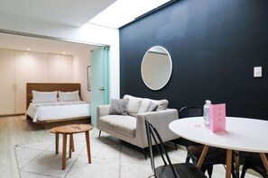 A modern hotel room with a bed, a sofa, a small table, and a round table.