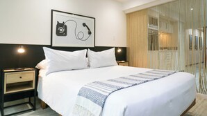 A hotel room with a large bed, two bedside tables, a framed picture on the wall, and a window with curtains.
