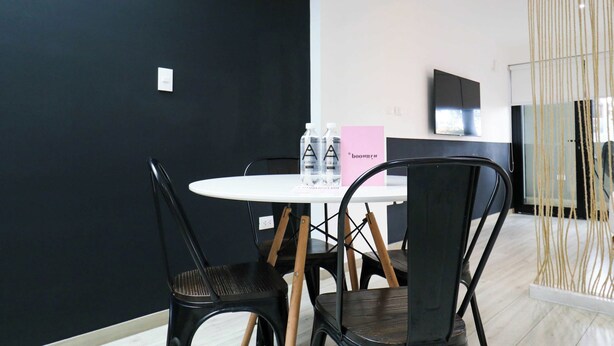 A modern room with a round table, black chairs, a flat-screen TV, and a decorative rope installation.