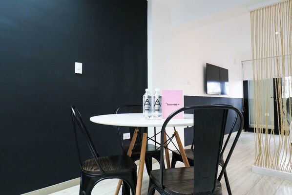 A modern room with a round table, black chairs, a flat-screen TV, and a decorative rope installation.