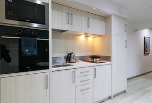 A modern kitchen with a built-in oven, microwave, and a kettle on the countertop.