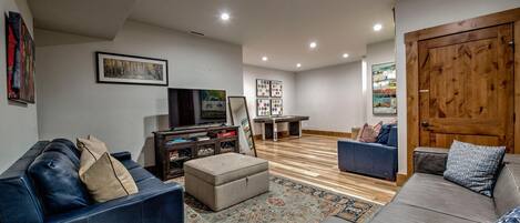 Un salón amplio con una televisión grande, mesa de billar y zonas de estar cómodas.