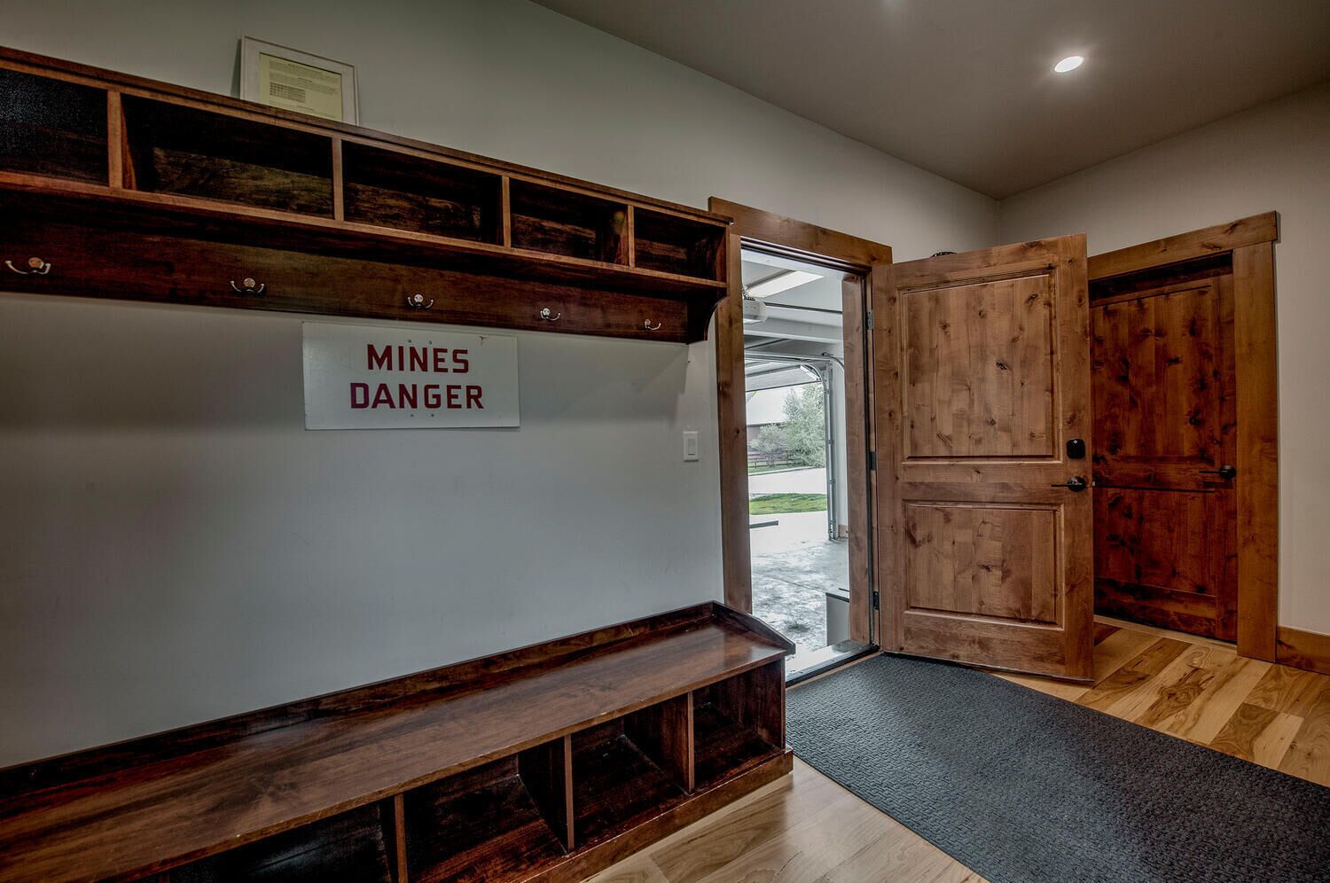 A hallway with a sign reading "MINES DANGER," wooden shelves, and a double door.