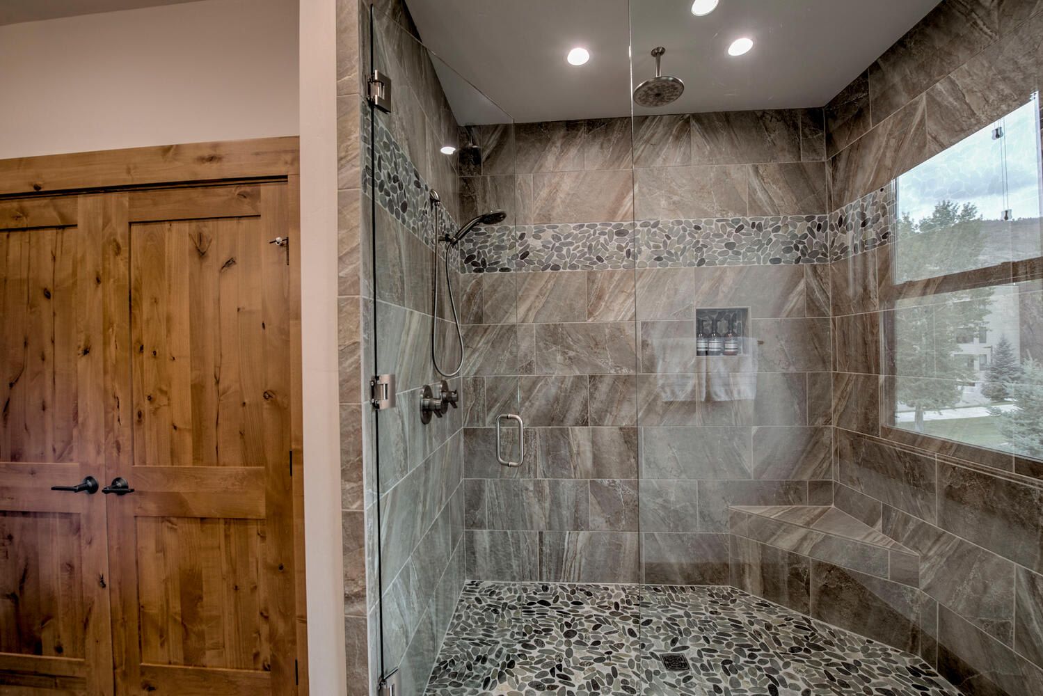 Un baño moderno con ducha, paredes de azulejos y una puerta de madera.