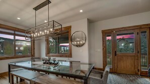 Un espace de repas moderne avec une table en verre, des bancs en bois et un luminaire suspendu.