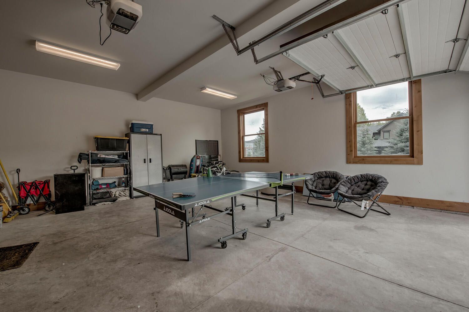 Una habitación amplia con mesa de ping-pong, bicicleta y una silla cómoda.