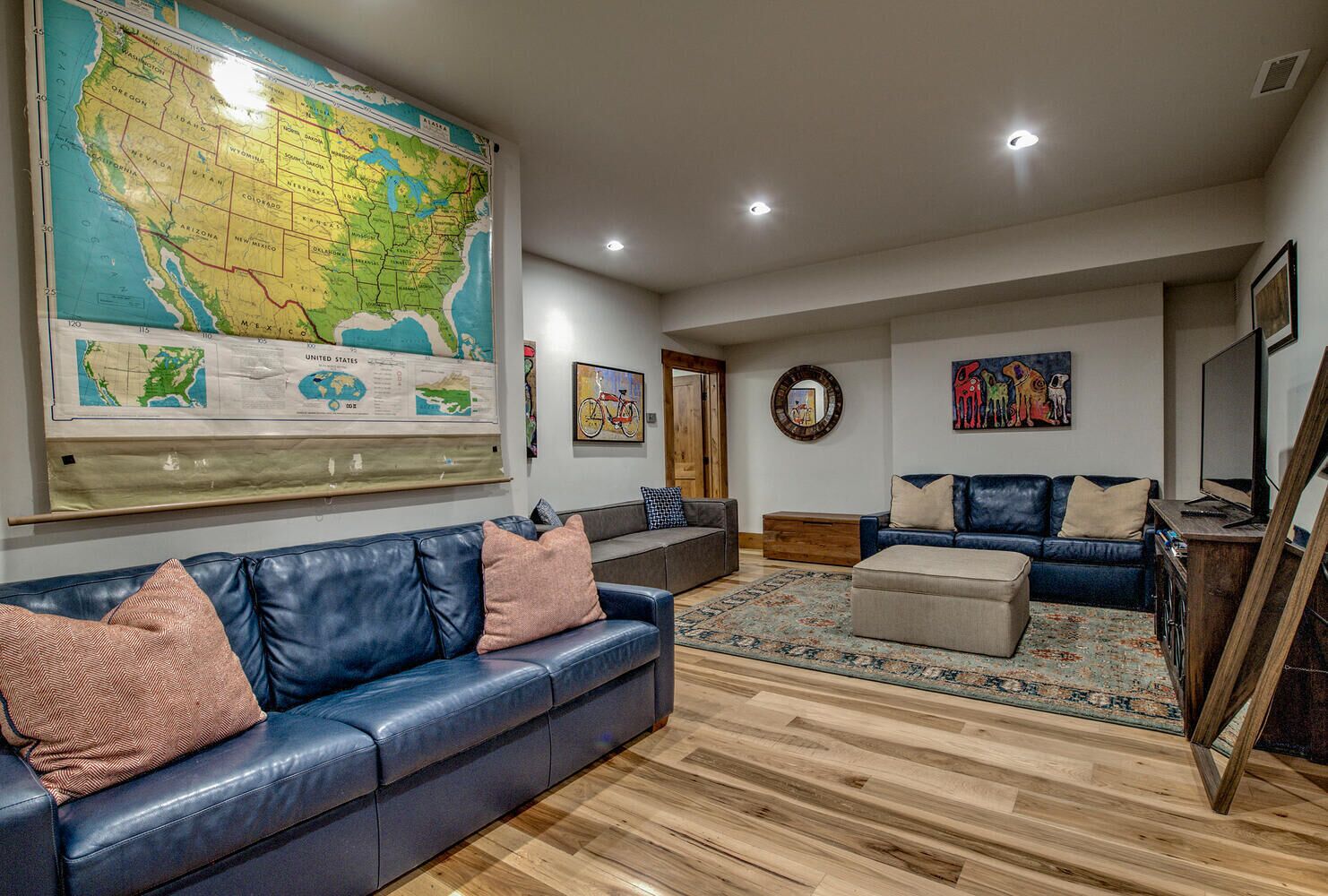 A living room with a large map, leather sofas, a coffee table, and a TV.