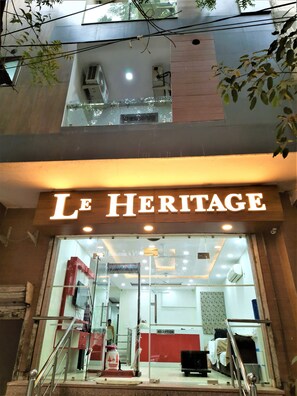 The entrance of Le Heritage hotel with a reception desk and a staircase leading to the upper floor.