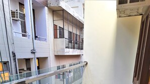 Un couloir doté d’une rambarde en verre, d’un sol carrelé et offrant une vue sur les bâtiments adjacents.