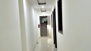 Un couloir propre et bien éclairé, avec un sol carrelé, un escalier au fond et un extincteur fixé au mur.