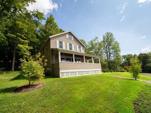 A two-story house with a front porch, surrounded by a well-maintained lawn and trees.