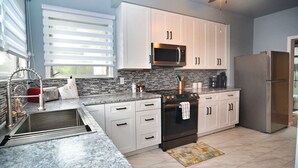 A modern kitchen with white cabinets, a stainless steel refrigerator, a microwave, and a built-in oven.