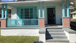 A house with a porch, a brick foundation, and a black door.