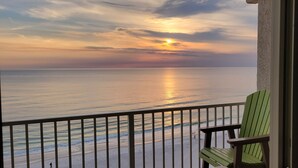 En balkon med udsigt over havet i solnedgang.