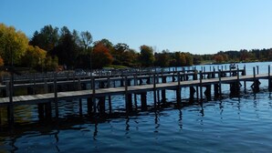 Een houten steiger die zich uitstrekt over rustig water, omringd door bomen met herfstbladeren.