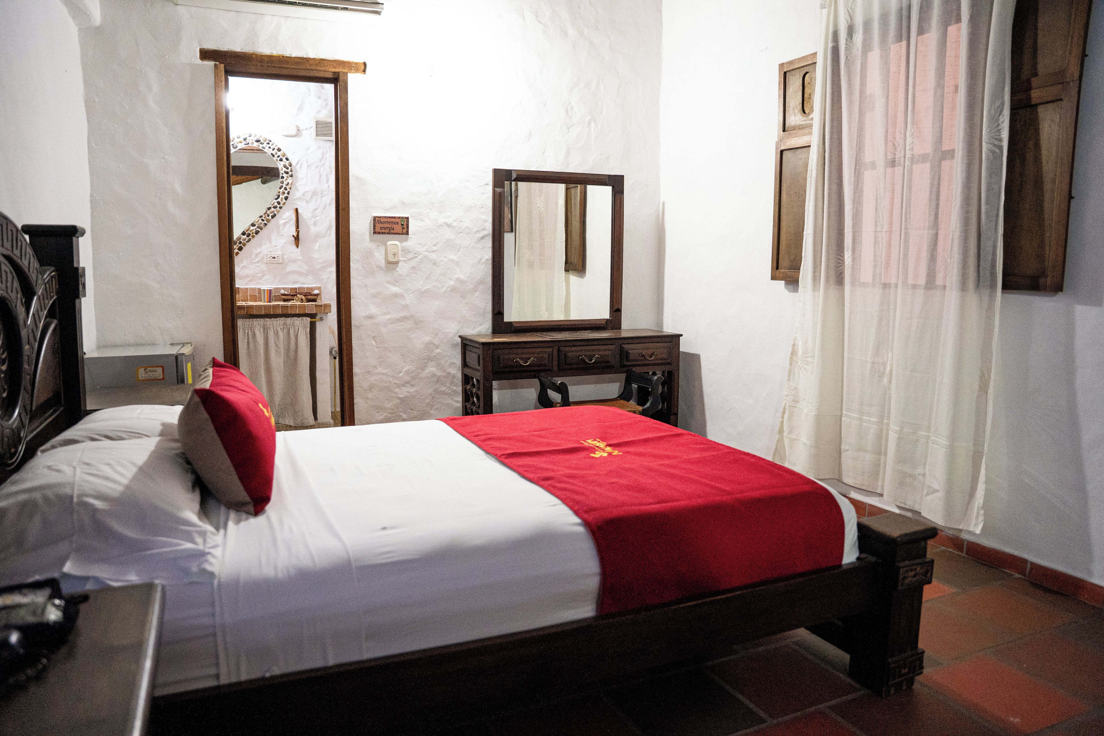 A bedroom with a bed, a dresser, a mirror, and a door.